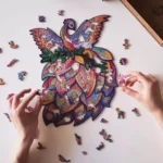 Persona che assembla un colorato puzzle Dragon Animali su una superficie bianca.