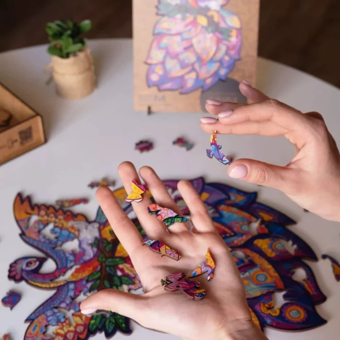 Mani che assemblano un puzzle colorato a forma di Fairy Bird Unidragon Animali su un tavolo di legno.