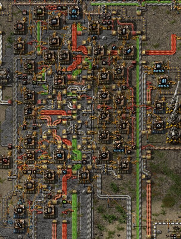 Una complessa rete di macchinari, nastri trasportatori e bracci robotici lavora i materiali in uno stabilimento industriale visto dall’alto.
